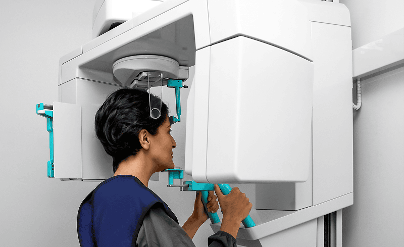 Person using dental X-ray machine.