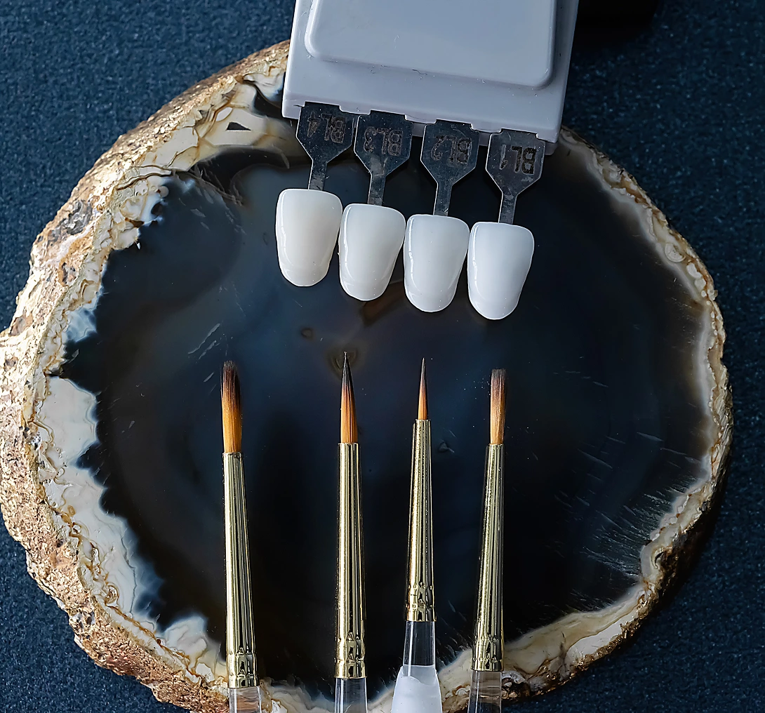Dental crowns and brushes on stone slab.