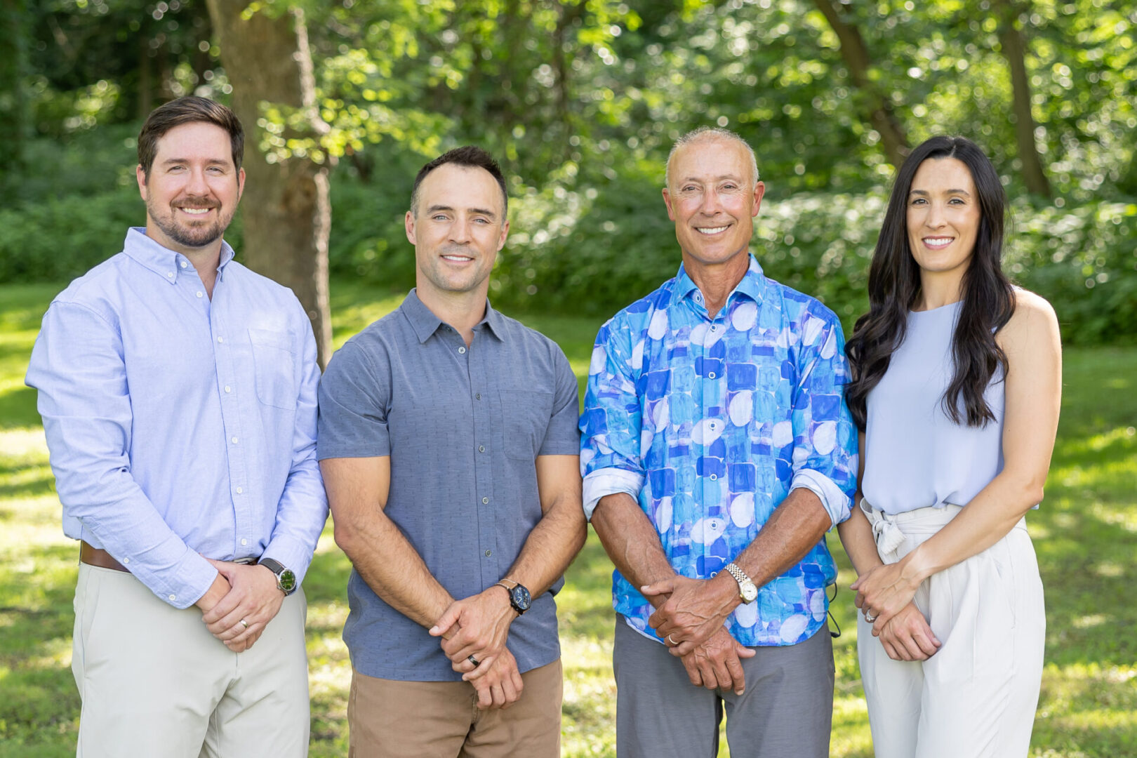 Four people standing in a sunny park.